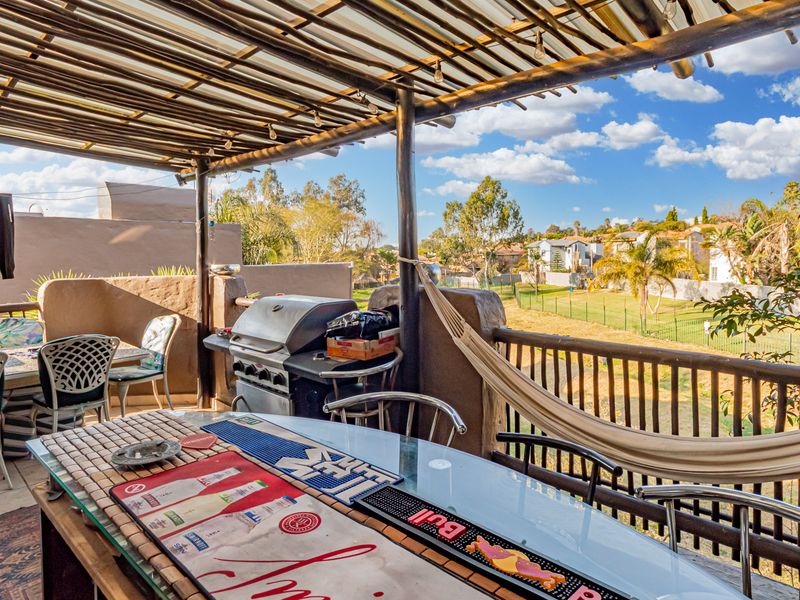 Covered outdoor patio area featuring a timber pergola, tiled flooring, and views over the surrounding estate grounds.