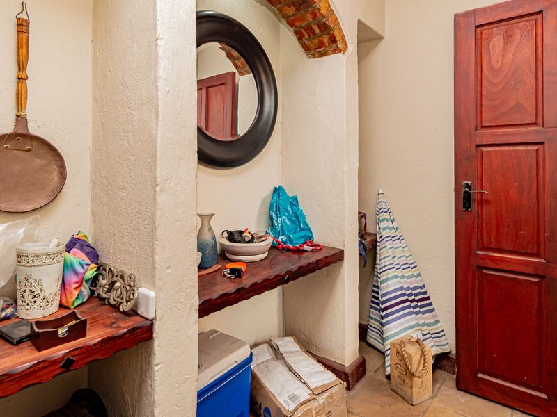 An entry area featuring rustic timber shelving, a solid wood door, and a decorative exposed brick archway detail.