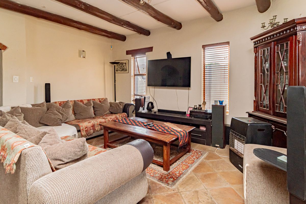 Cozy living room featuring rustic exposed timber ceiling beams and traditional terracotta floor tiles, creating a warm and inviting atmosphere.