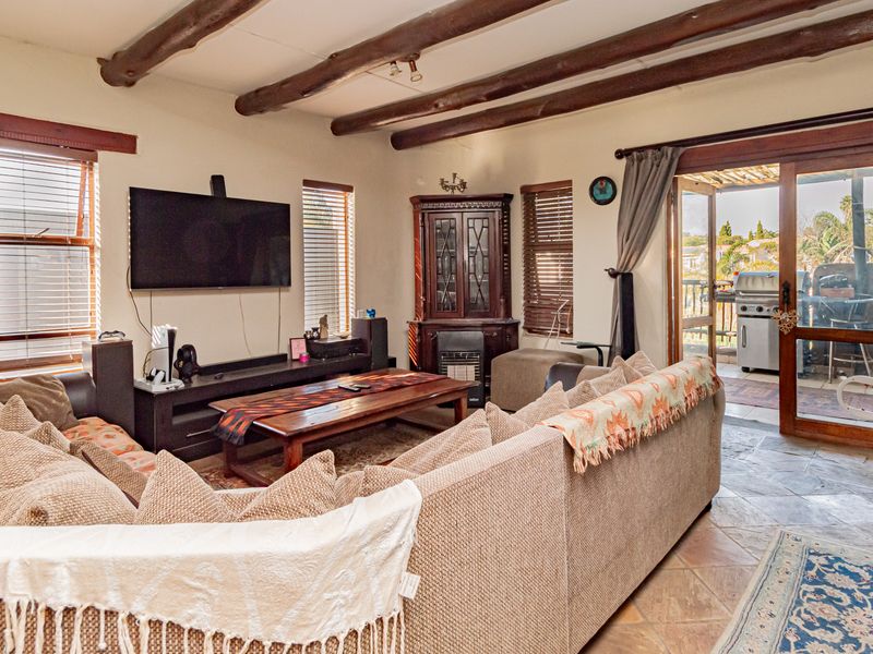 Spacious living room featuring exposed timber ceiling beams, tiled flooring, and direct access to an outdoor patio area through sliding glass doors.
