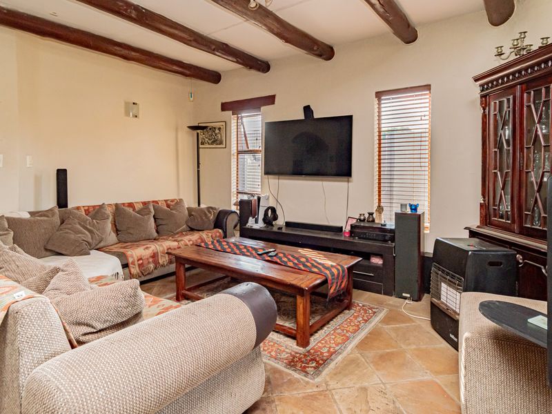 Cozy living room featuring rustic exposed timber ceiling beams and traditional terracotta floor tiles, creating a warm and inviting atmosphere.