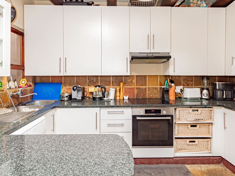 A functional kitchen featuring white cabinetry, granite countertops, a built-in oven, electric cooktop, and a tiled backsplash.