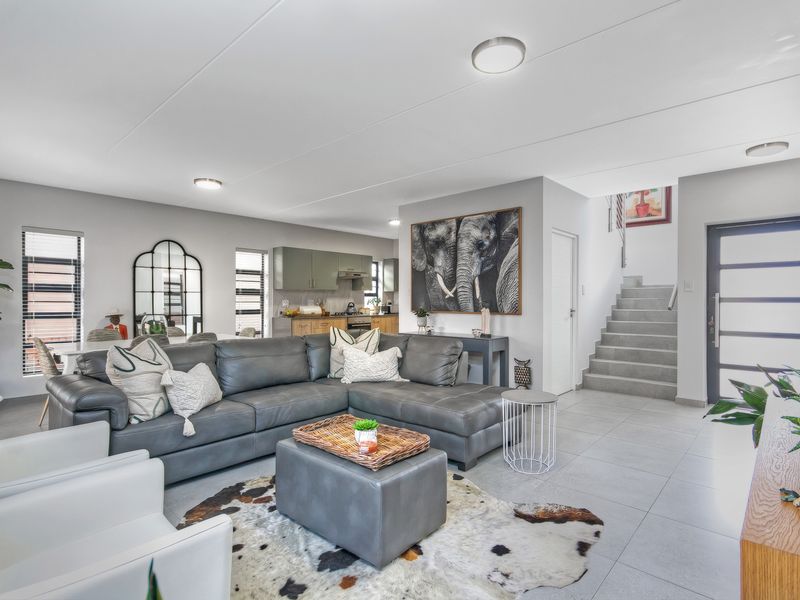 Open-plan living area featuring tiled flooring, a modern kitchen with built-in cabinetry, and a staircase leading to the upper level.