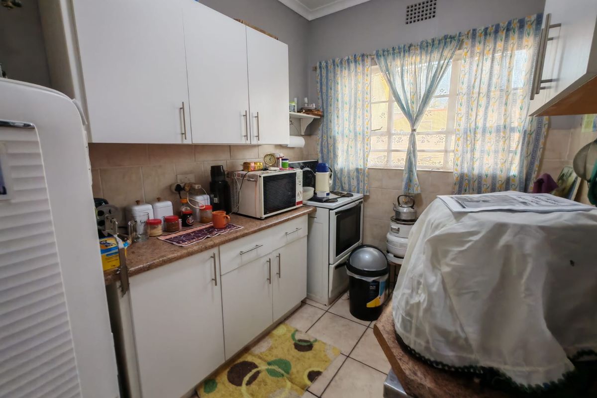 A functional kitchen featuring white cabinetry, tiled backsplash, tiled flooring, and a window providing natural light.