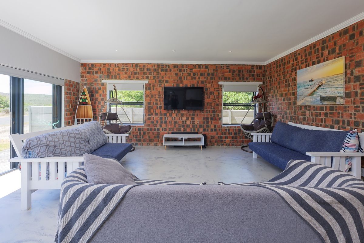 Spacious living room featuring exposed brick walls, polished concrete floors, and large sliding glass doors providing natural light and outdoor access.