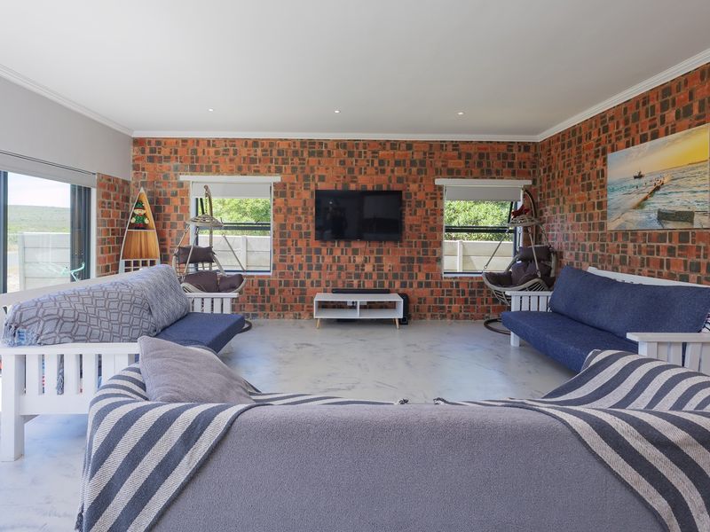 Spacious living room featuring exposed brick walls, polished concrete floors, and large sliding glass doors providing natural light and outdoor access.