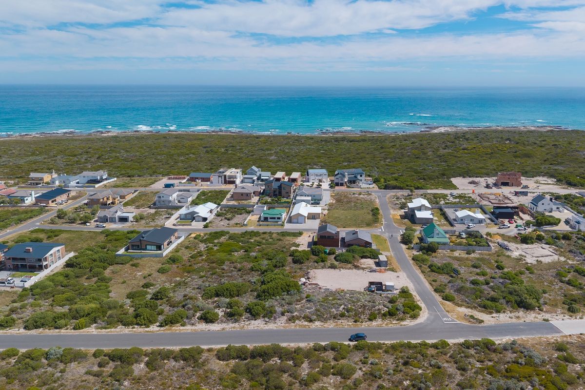 An aerial view of a coastal residential estate featuring multiple detached houses situated near the ocean shoreline.