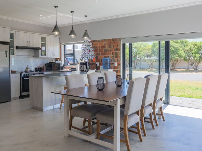 Spacious open-plan kitchen and dining area featuring exposed brick accents, modern cabinetry, and large sliding doors providing seamless access to the outdoor space.