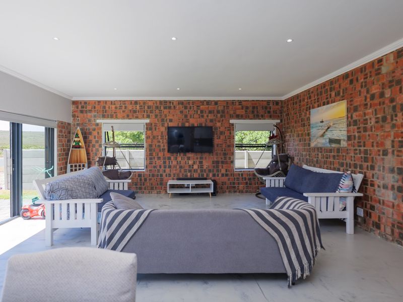 Spacious living room featuring exposed brick walls, polished concrete floors, and large sliding glass doors providing seamless access to the outdoor area.