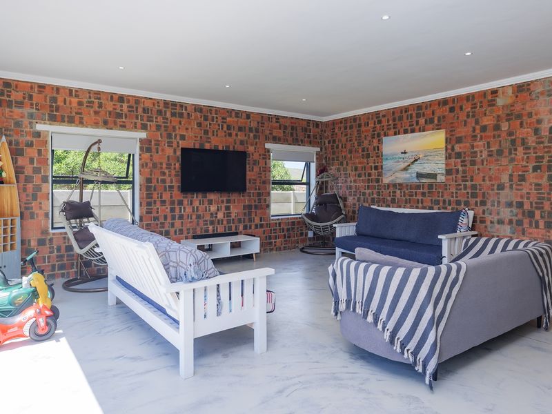 Spacious living room featuring exposed brick walls, polished concrete flooring, and large sliding glass doors providing ample natural light.