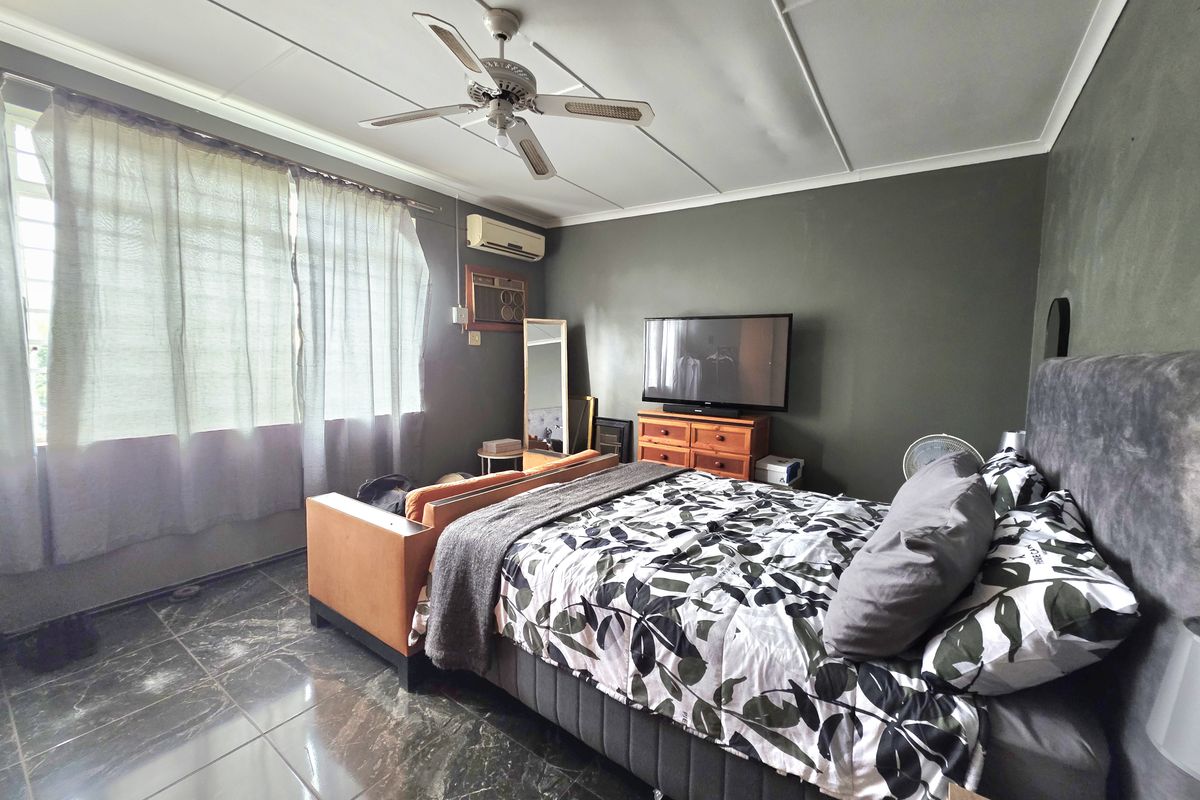 A bedroom featuring dark tiled flooring, a ceiling fan, and a wall-mounted air conditioning unit.