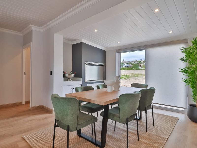 Modern dining area featuring a built-in braai, tongue and groove ceiling, recessed lighting, and large sliding doors leading to an outdoor view.