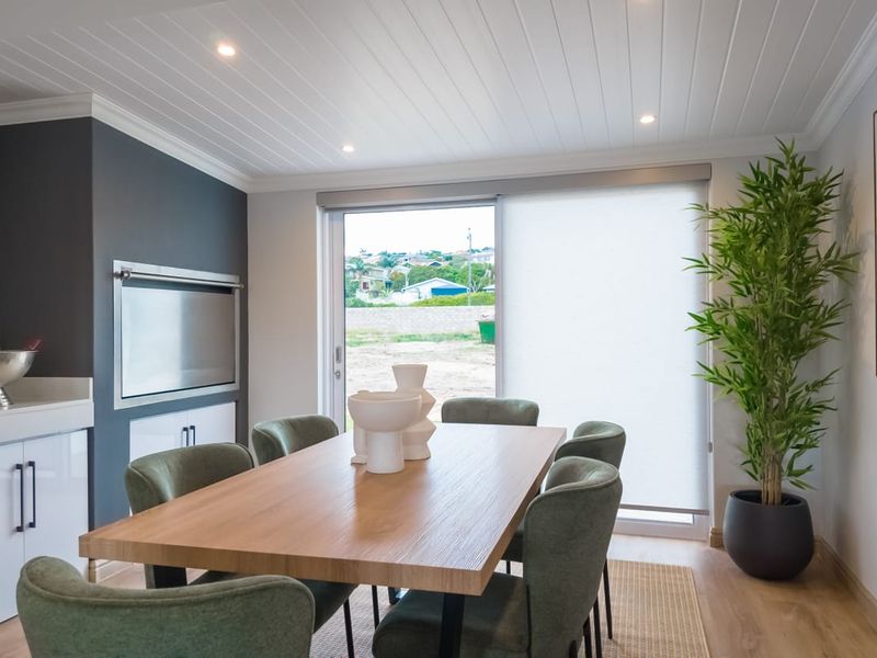 Modern dining room featuring a built-in braai, tongue and groove ceiling, and sliding glass doors leading to the exterior.