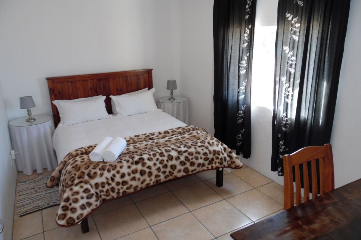 A functional bedroom featuring tiled flooring and a window with dark curtains, providing a simple and practical living space.