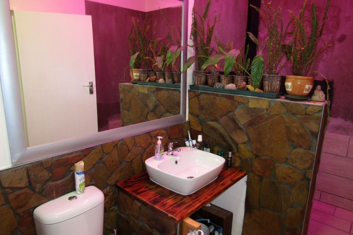 Bathroom featuring a vessel sink on a wooden vanity, stone wall cladding, and a large wall-mounted mirror.