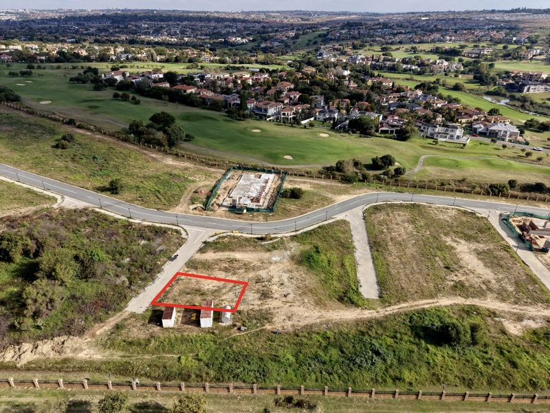 Aerial view of a vacant residential plot in a developed estate, featuring road access and proximity to a golf course.