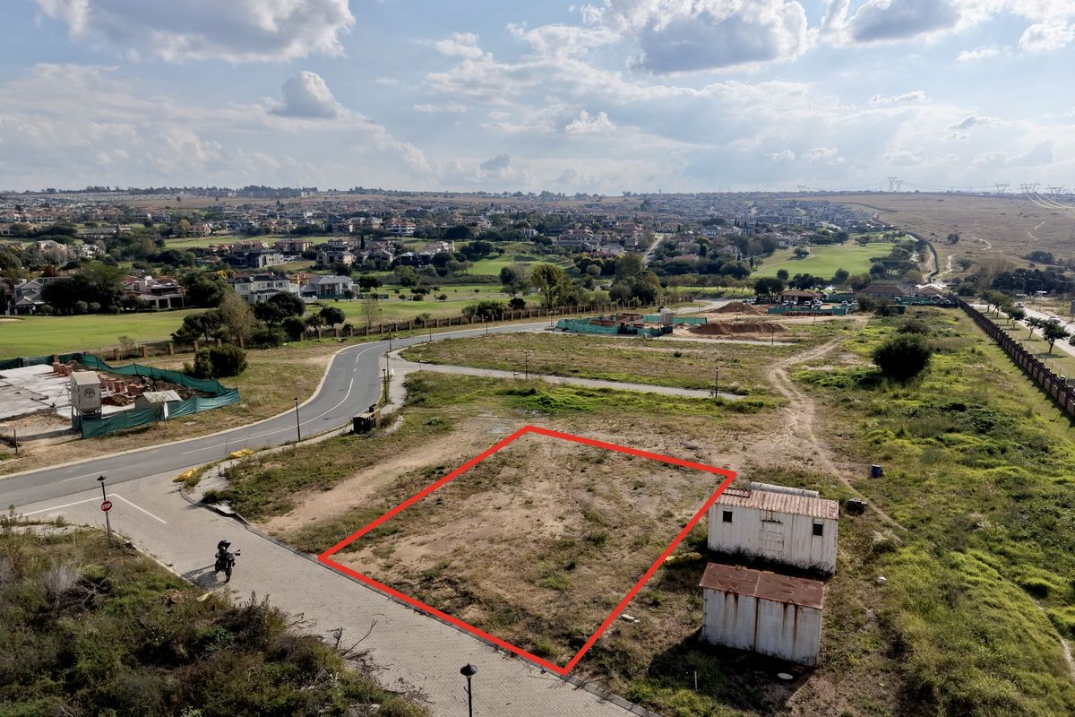 Aerial view of a vacant residential plot featuring a red boundary outline, situated in a developed estate with surrounding road infrastructure.