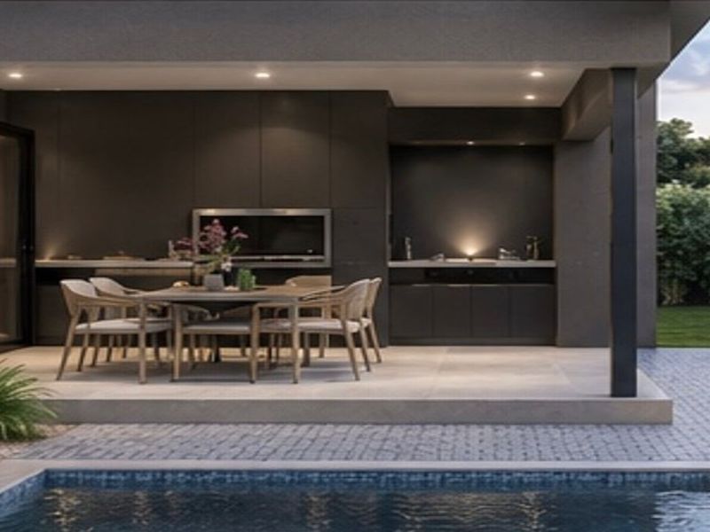 A modern covered patio featuring a built-in braai, sleek cabinetry, and recessed lighting, overlooking a swimming pool and landscaped garden.
