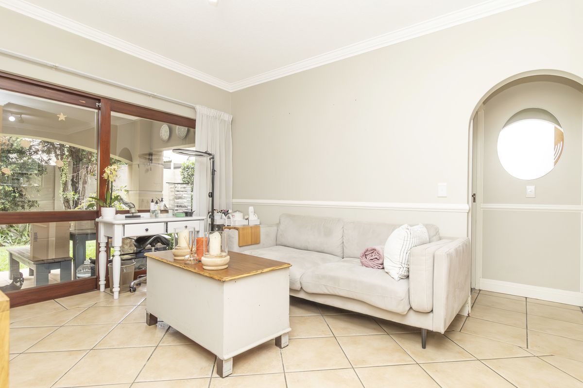 A living room featuring tiled flooring, crown molding, wainscoting, and a large sliding glass door providing access to the outdoor area.