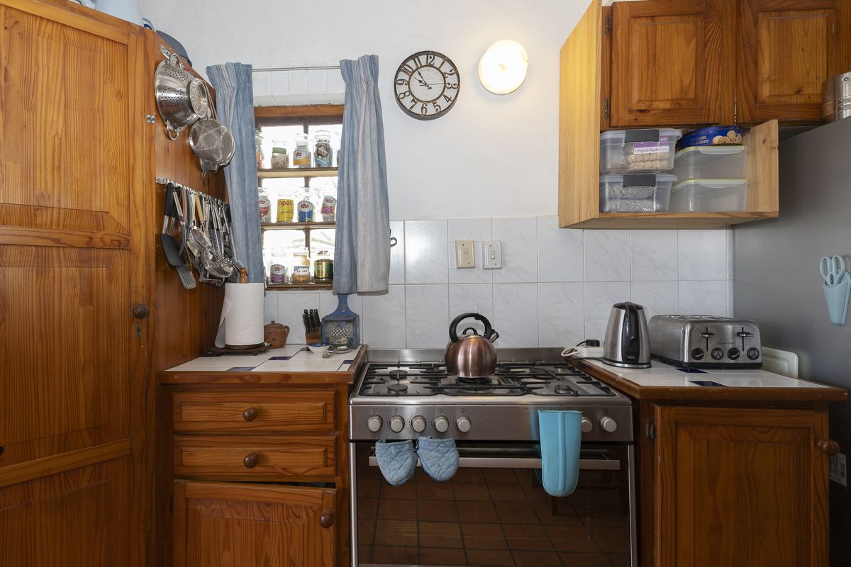 A compact kitchen featuring traditional wooden cabinetry, a gas stove, and tiled backsplash, offering a functional layout with potential for modern updates.