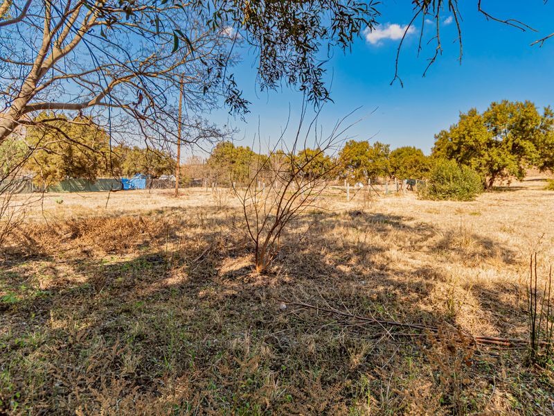A view of the expansive, undeveloped garden area featuring mature trees and perimeter fencing on the small holding property.