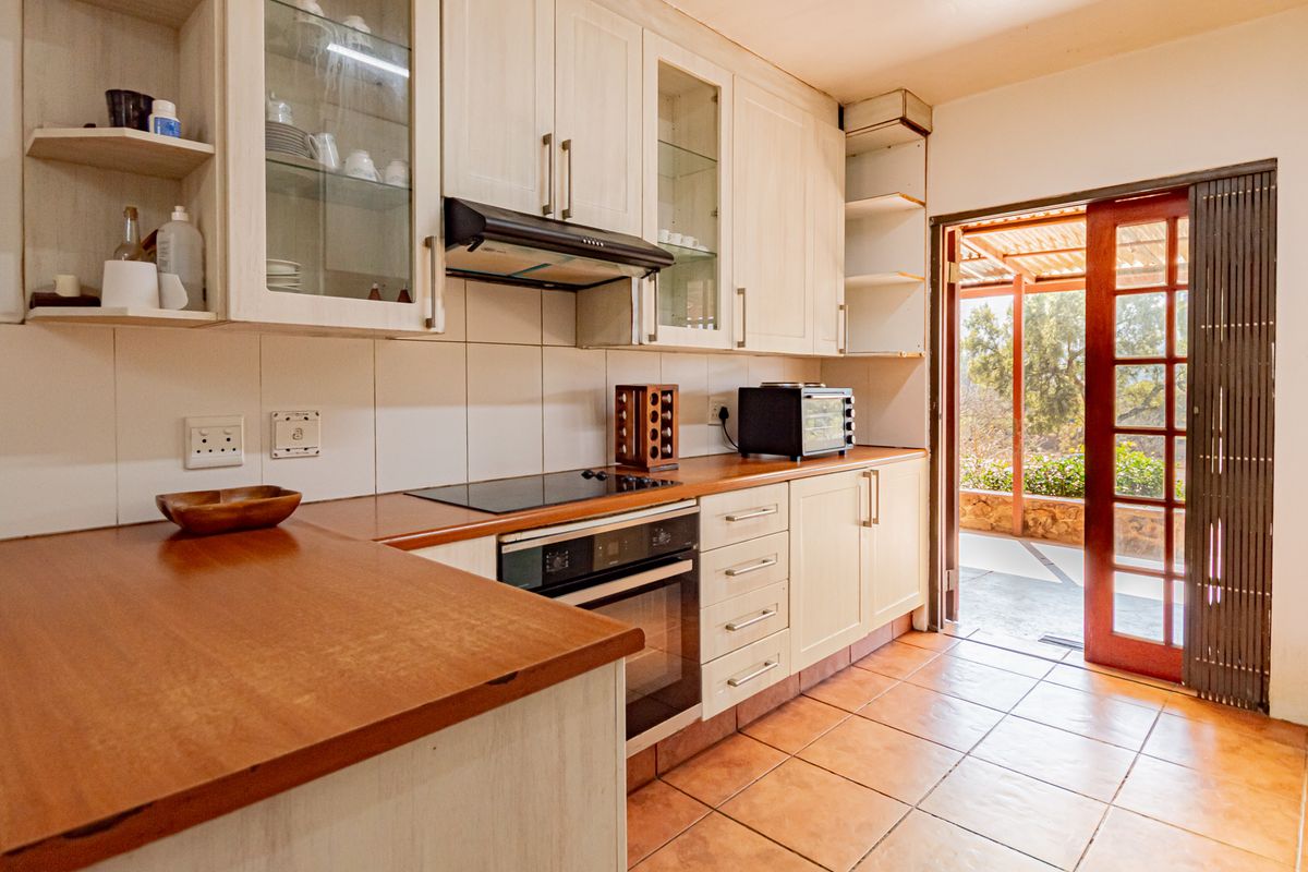 Functional kitchen featuring wooden countertops, built-in oven and hob, ample cabinetry, and direct access to an outdoor patio area.