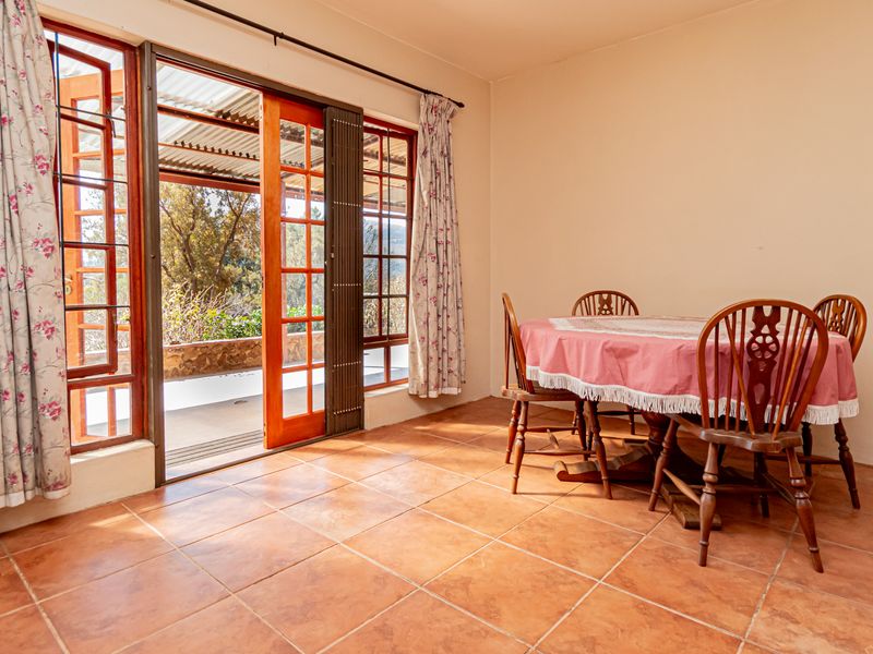 Dining room featuring terracotta floor tiles and large wooden sliding doors providing direct access to a covered patio area.