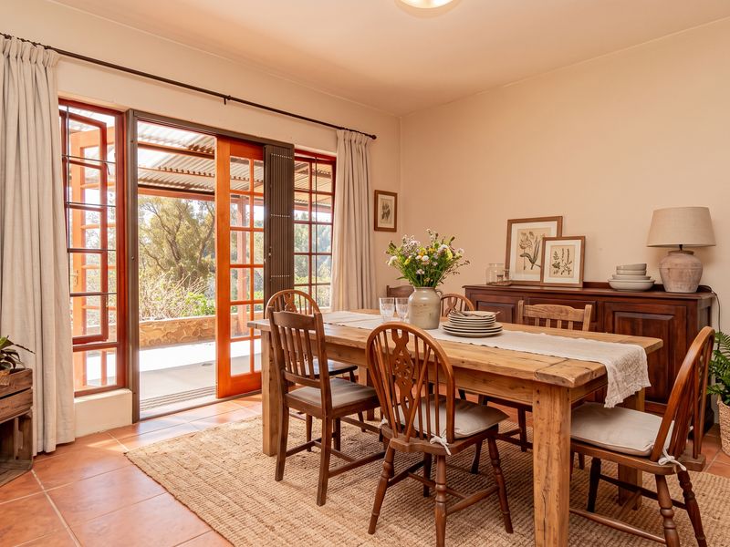 A bright dining room featuring terracotta floor tiles and wooden framed sliding doors that provide direct access to an outdoor patio area.
