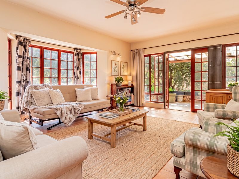 A bright and inviting living room featuring tiled flooring, a ceiling fan, and large windows with direct access to an outdoor patio area.