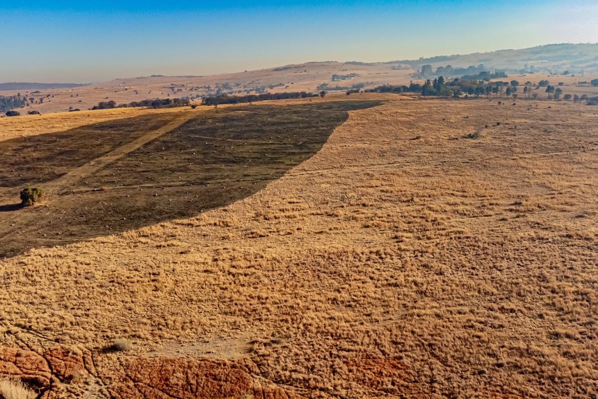 An aerial view of a large, open tract of vacant residential land featuring natural grassland and rolling terrain.