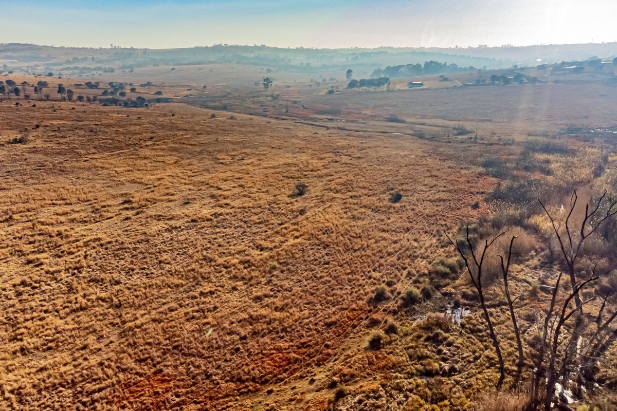 An aerial view of expansive, undeveloped residential land featuring natural grassland and rolling terrain.