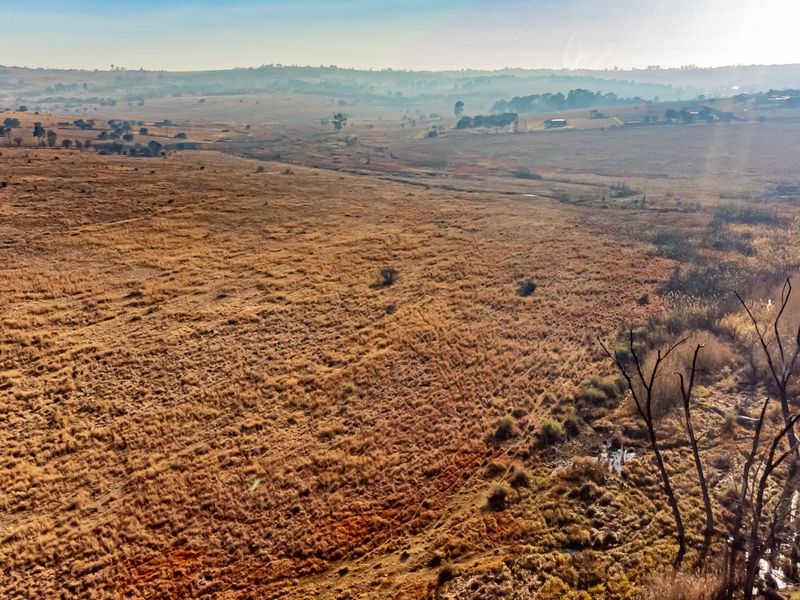 An aerial view of expansive, undeveloped residential land featuring natural grassland and rolling terrain.