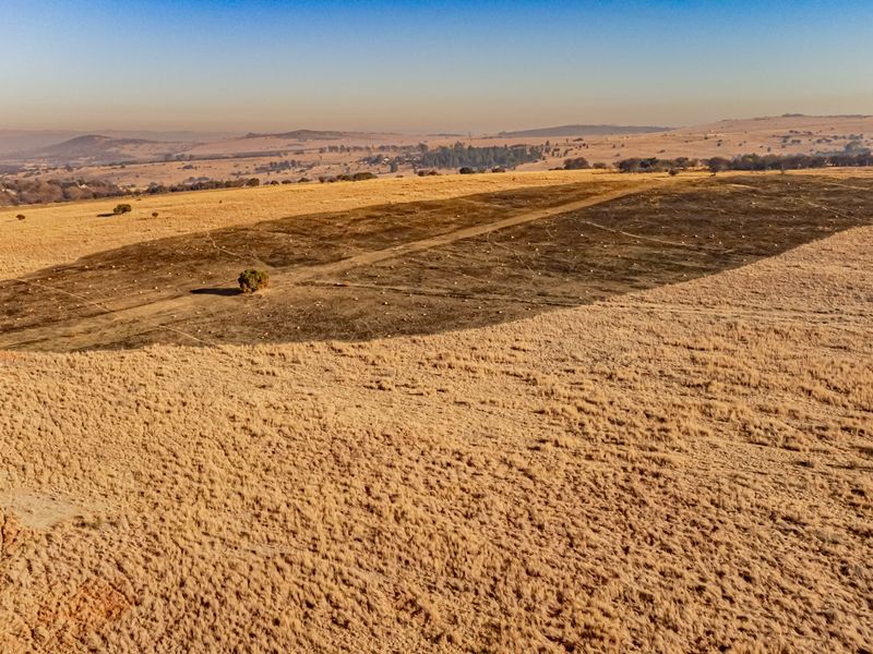 An aerial view of a large, open residential vacant land plot featuring natural grassland and expansive landscape views.