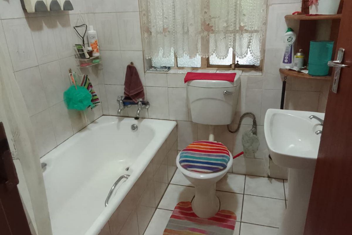 A compact bathroom featuring a standard bathtub, pedestal basin, and toilet with tiled wall and floor finishes.
