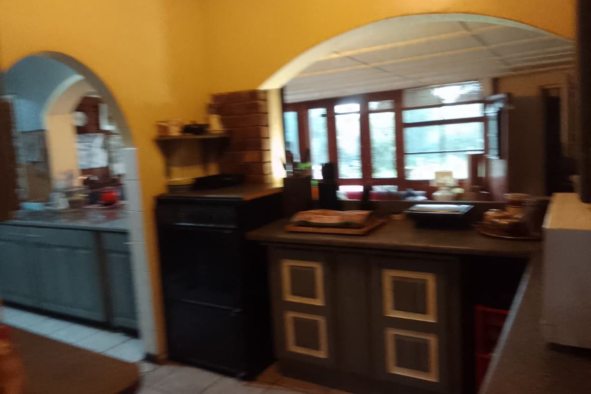 A dated kitchen area featuring traditional archways, built-in cabinetry, and tiled flooring, offering potential for a modern renovation.