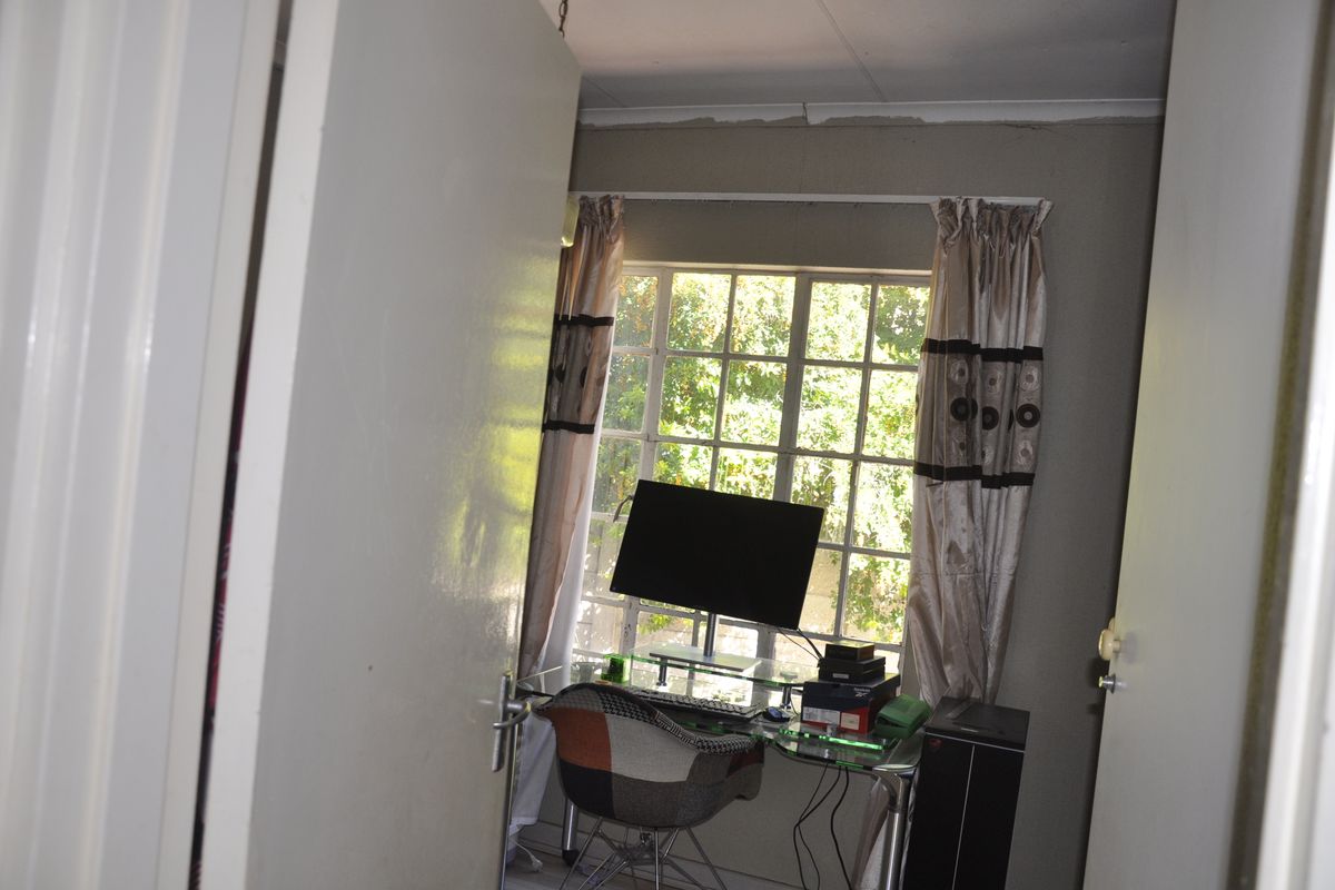 A small bedroom or home office space featuring a large window with natural light and standard door access.