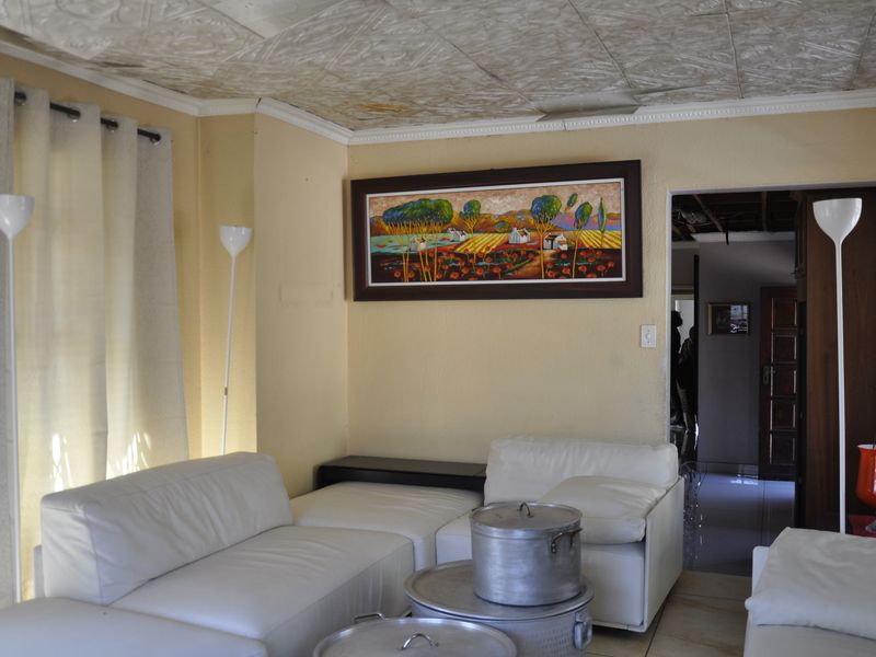 A living room featuring a textured ceiling, tiled flooring, and access to an adjoining hallway.