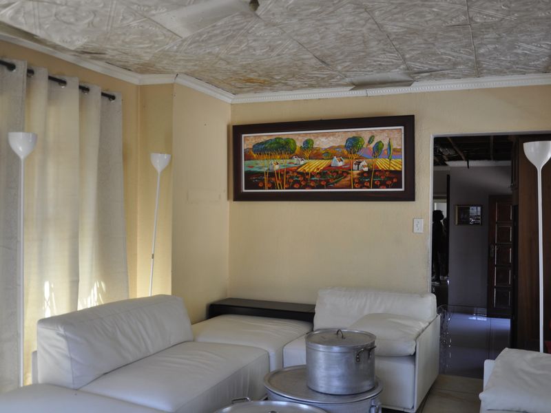A living room featuring a textured ceiling, neutral wall tones, and access to an adjacent hallway.