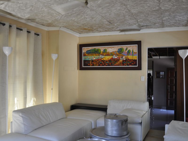 A living room featuring a textured ceiling and access to an adjacent hallway, providing a functional space with potential for cosmetic updates.