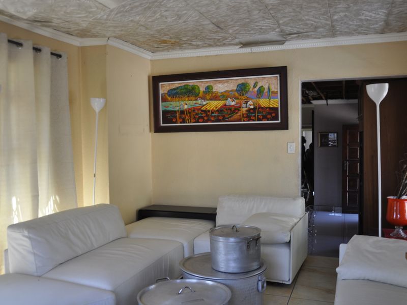 A living room featuring tiled flooring and a textured ceiling, with a doorway leading to an adjacent interior space.