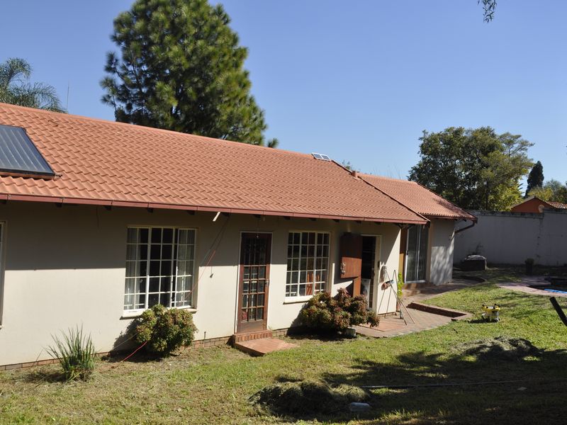 Rear view of the house featuring a tiled roof with solar water heating panels, brick patio area, and access to the garden.