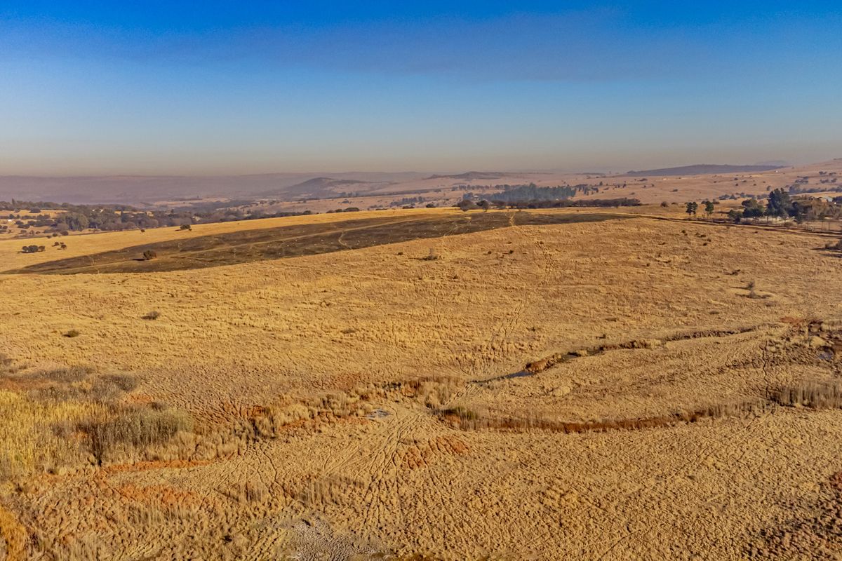 An aerial view of a large, open residential vacant land plot featuring natural grassland and expansive landscape views.