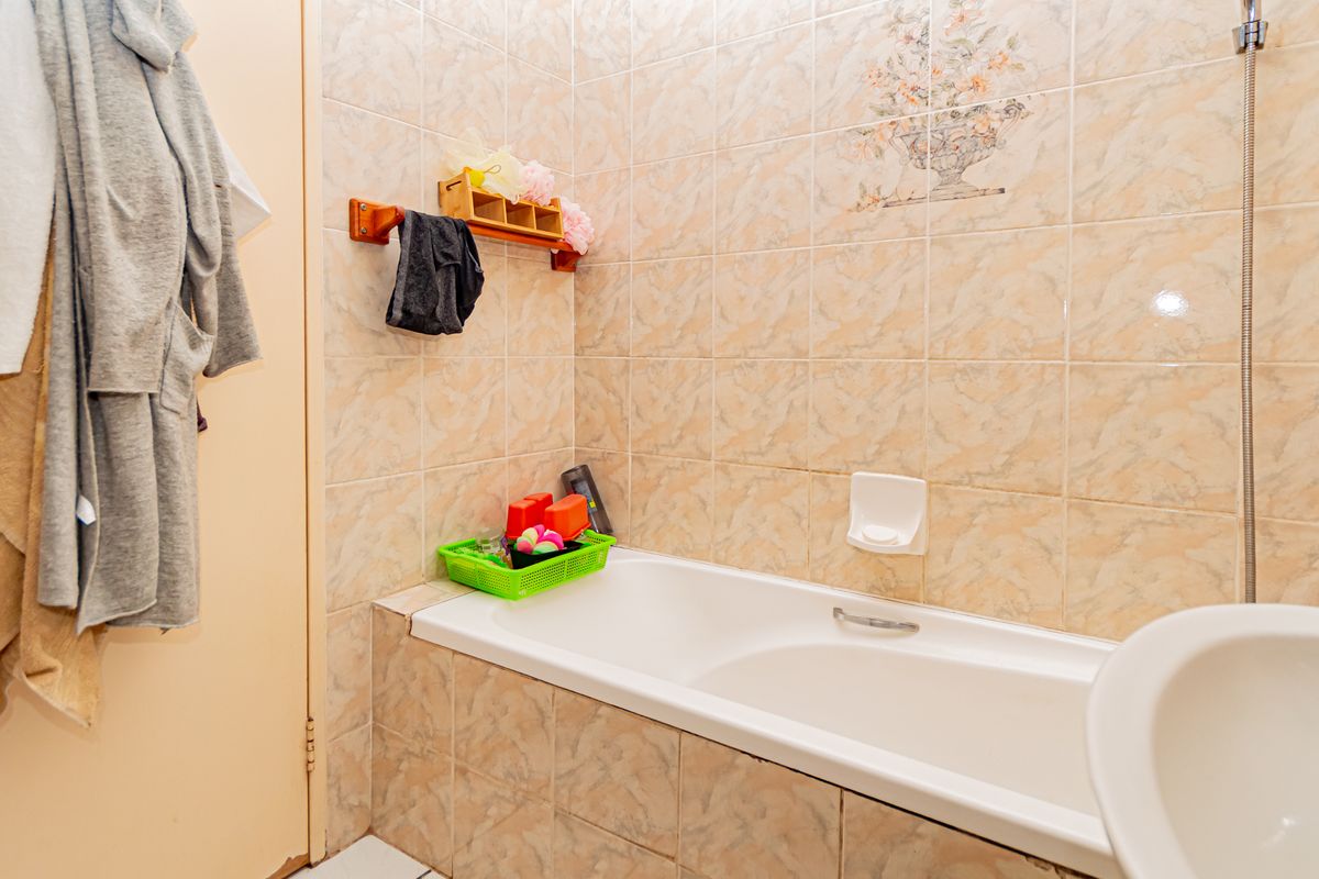 A functional bathroom featuring a built-in bathtub with tiled surround and wall-mounted shower fixtures.