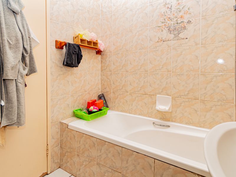 A functional bathroom featuring a built-in bathtub with tiled surround and wall-mounted shower fixtures.
