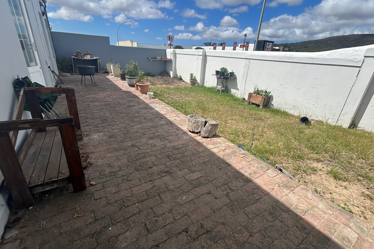 A rear courtyard area featuring brick paving and a high boundary wall, offering a private outdoor space with potential for landscaping improvements.