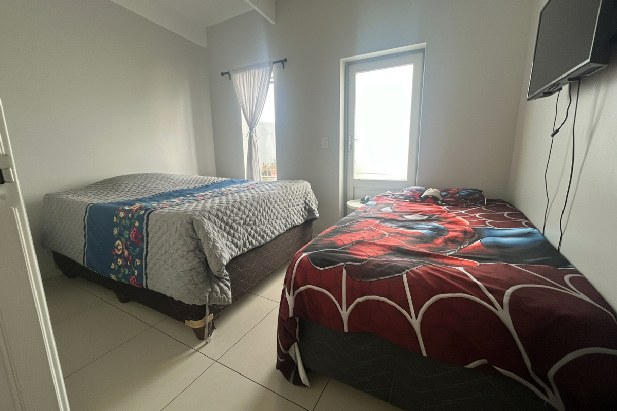 A bedroom featuring tiled flooring and a glass panel door providing natural light, with wall-mounted television connectivity.