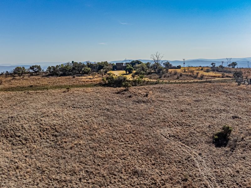 An aerial view of a large, undeveloped residential plot featuring natural vegetation and open terrain.