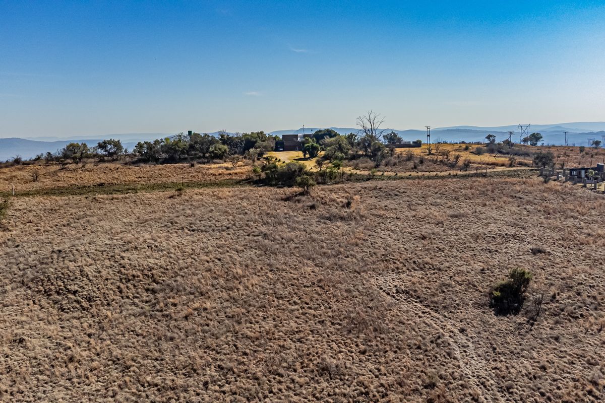 An aerial view of a large, undeveloped residential plot featuring natural vegetation and open terrain.