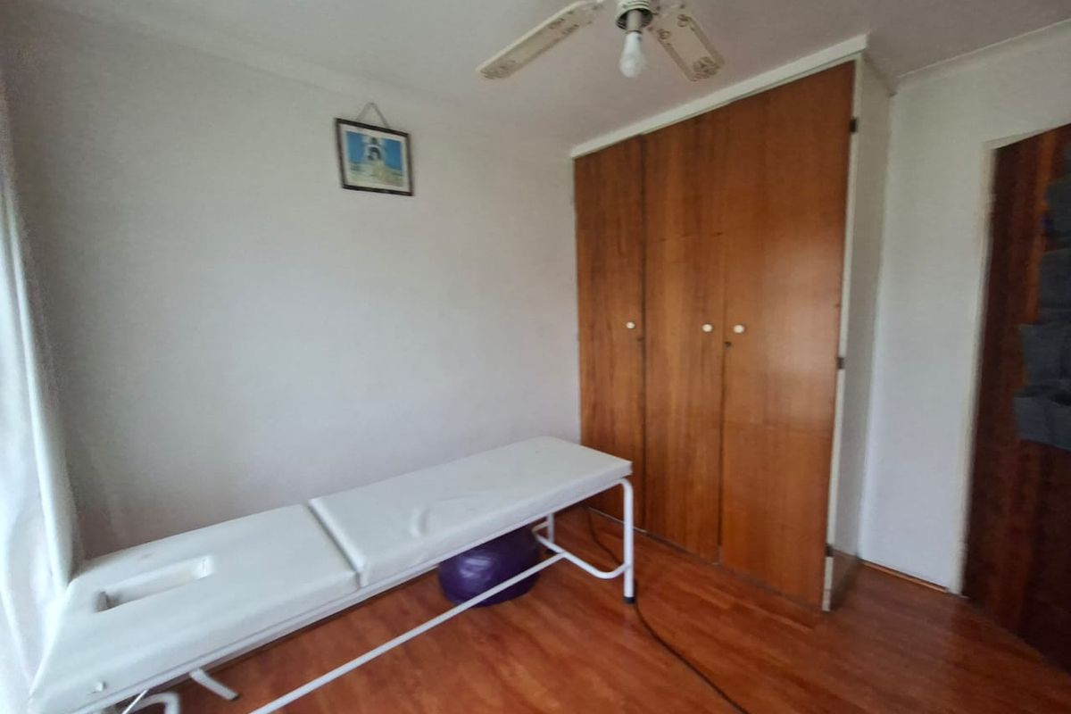 A bedroom featuring built-in wooden wardrobes, laminate flooring, and a ceiling fan.
