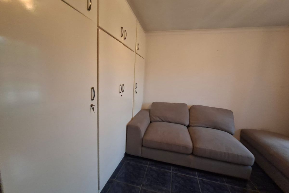 A bedroom featuring built-in cupboards and dark tiled flooring, offering a functional space with potential for modern updates.